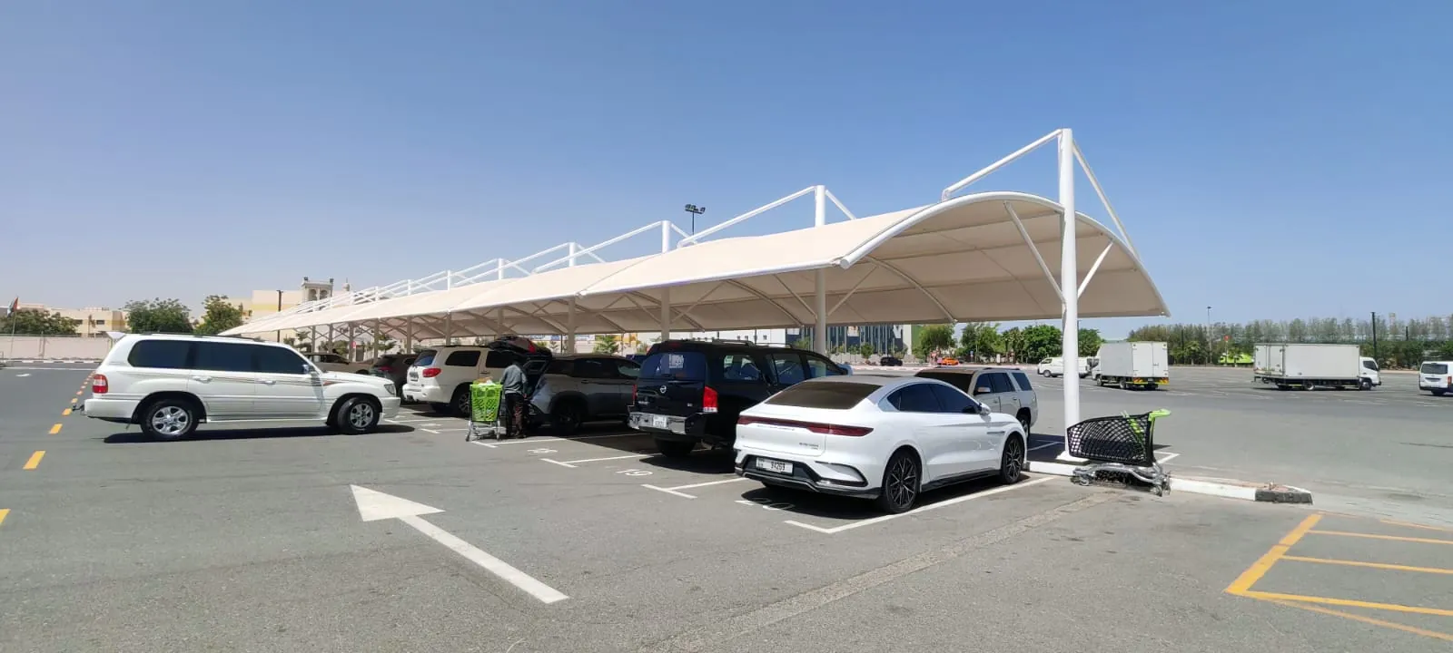Long white tensile car parking shade at a shopping centre car park in the UAE