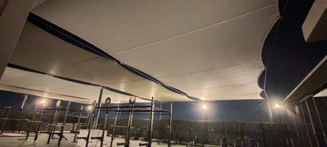 Tensile fabric shade over a rooftop gym in Dubai, lit at night